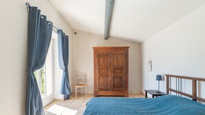 Un dormitorio con cama, un armario de madera, una silla y una mesita.