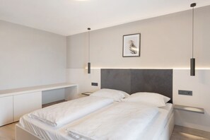 Ein modernes Schlafzimmer mit einem Bett, Nachttischen und einer wandmontierten Lampe.