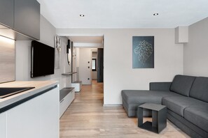 A modern kitchen with a flat-screen TV, grey sofa, and a small side table. - Apartment 'Magdalena' with Mountain View, Shared Pool and Wi-Fi (Marling)