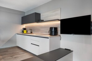 Una cucina moderna con una TV a schermo piatto, una macchina per il caffè e una caffettiera sul piano di lavoro.