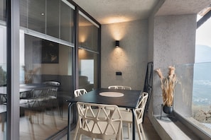 Un balcone moderno con tavolo e sedie, una pianta in vaso e vista sul paesaggio.