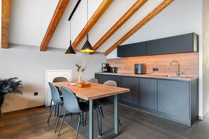 Een moderne keuken met een houten eettafel, grijze stoelen en hanglampen.