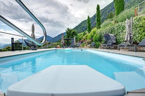 A swimming pool with lounge chairs and umbrellas, surrounded by greenery and mountains. - Apartment 'Victoria' with Mountain View, Shared Pool and Wi-Fi (Marling)