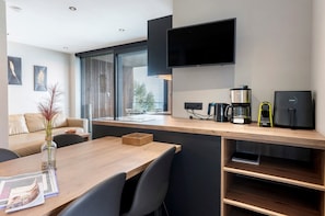 Een moderne keuken met een houten aanrecht, een koffiezetapparaat, een broodrooster en een aan de muur bevestigde televisie.