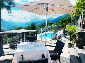 A table set outdoors with a pool and mountains in the background. - Apartment 'Victoria' with Mountain View, Shared Pool and Wi-Fi (Marling)