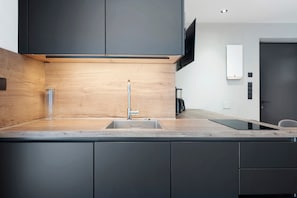 Een moderne keuken met een houten spatwand, een roestvrijstalen spoelbak en een inbouwoven.