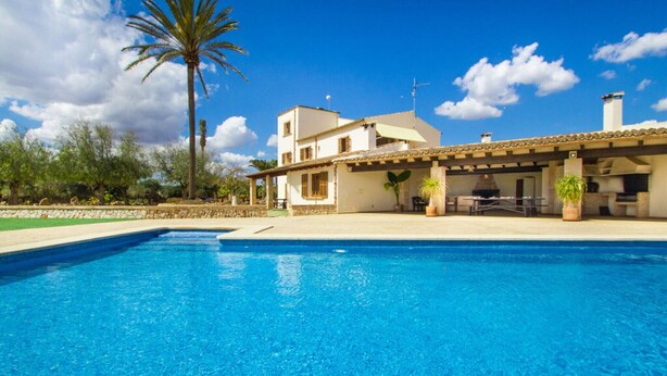 A swimming pool with a patio area, a white building with a tiled roof, and a palm tree. - Holiday Home 'Sant Blai Nou' with Private Pool, Private Terrace and Wi-Fi (Illes Balears)