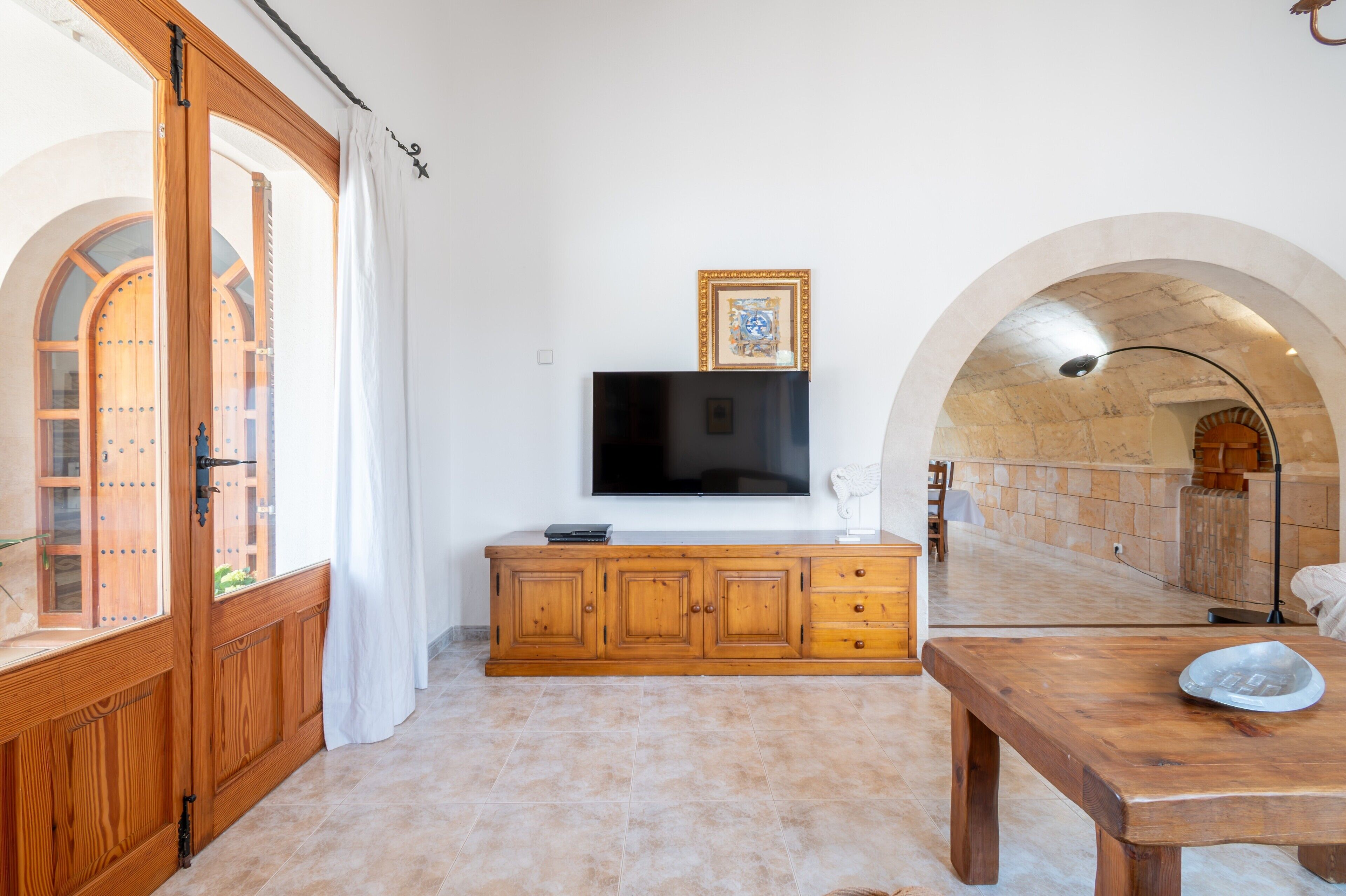 A room with a wooden cabinet, a television, and a dining table.