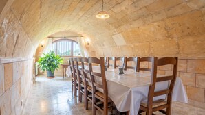 A dining area with a stone ceiling, wooden chairs, and a table set for six. - Holiday Home 'Sant Blai Nou' with Private Pool, Private Terrace and Wi-Fi (Illes Balears)