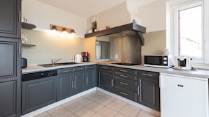 A modern kitchen with grey cabinets, a stainless steel range hood, a microwave, and a dishwasher. - Gîte d'Ayzi – Charming Rental with Panoramic Views, Ideal for Families or Friends, 15 Minutes from Lourdes (Ouzous)