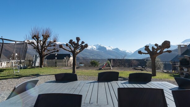 An outdoor seating area with a table and chairs, a playground, and a mountain view. - Gîte d'Ayzi – Charming Rental with Panoramic Views, Ideal for Families or Friends, 15 Minutes from Lourdes (Ouzous)