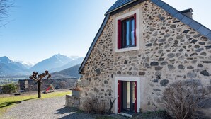 A stone building with a sloped roof and two windows with red shutters. - Gîte d'Ayzi – Charming Rental with Panoramic Views, Ideal for Families or Friends, 15 Minutes from Lourdes (Ouzous)