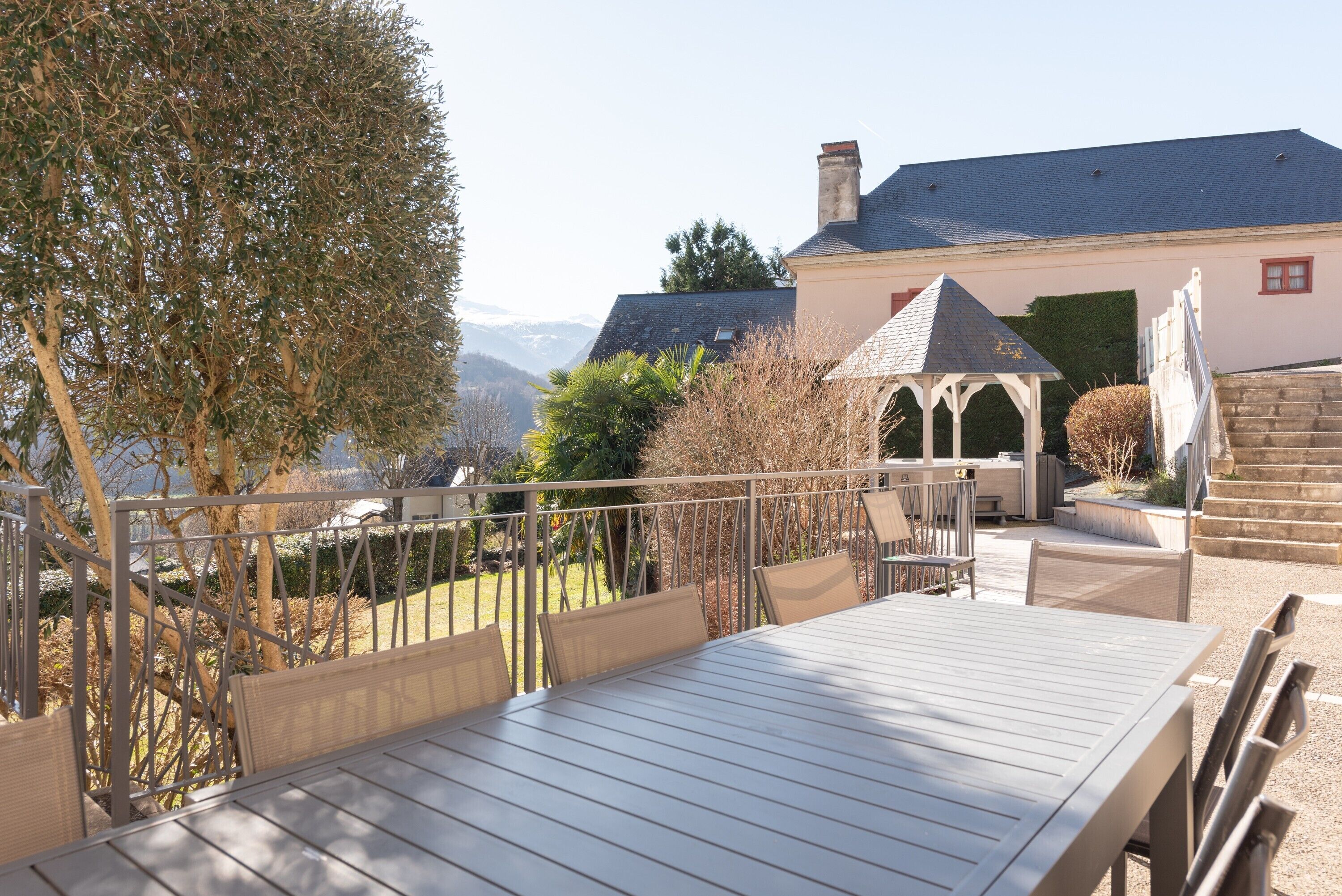 Um terraço com mesa e cadeiras, um gazebo e vista para montanhas.
