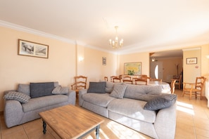 A living room with two sofas, a wooden coffee table, and a dining area with chairs and a table.