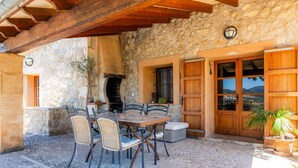 Un edificio de piedra con una mesa y sillas de madera, una chimenea y vistas al paisaje.