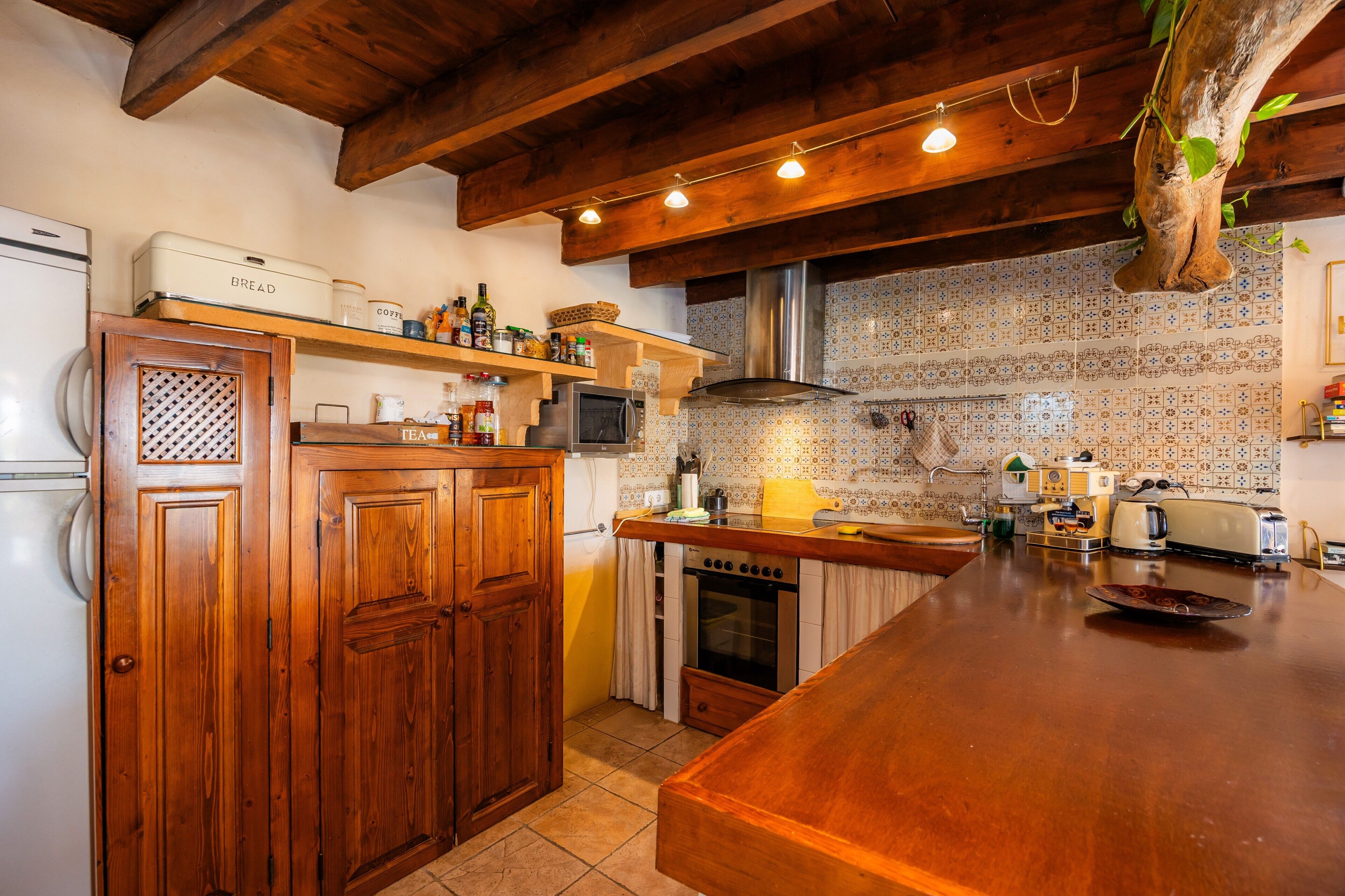 A kitchen with wooden cabinets, a bread machine, a microwave, and a toaster.