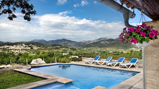 Piscina con sillas de descanso y vistas a un paisaje montañoso.