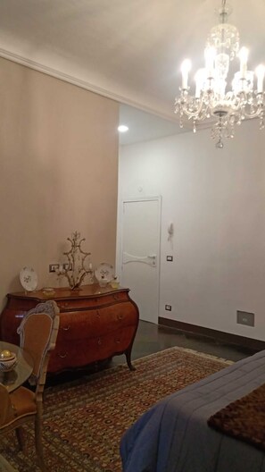 Une pièce avec un lustre, une commode en bois, une porte et un tapis à motifs.