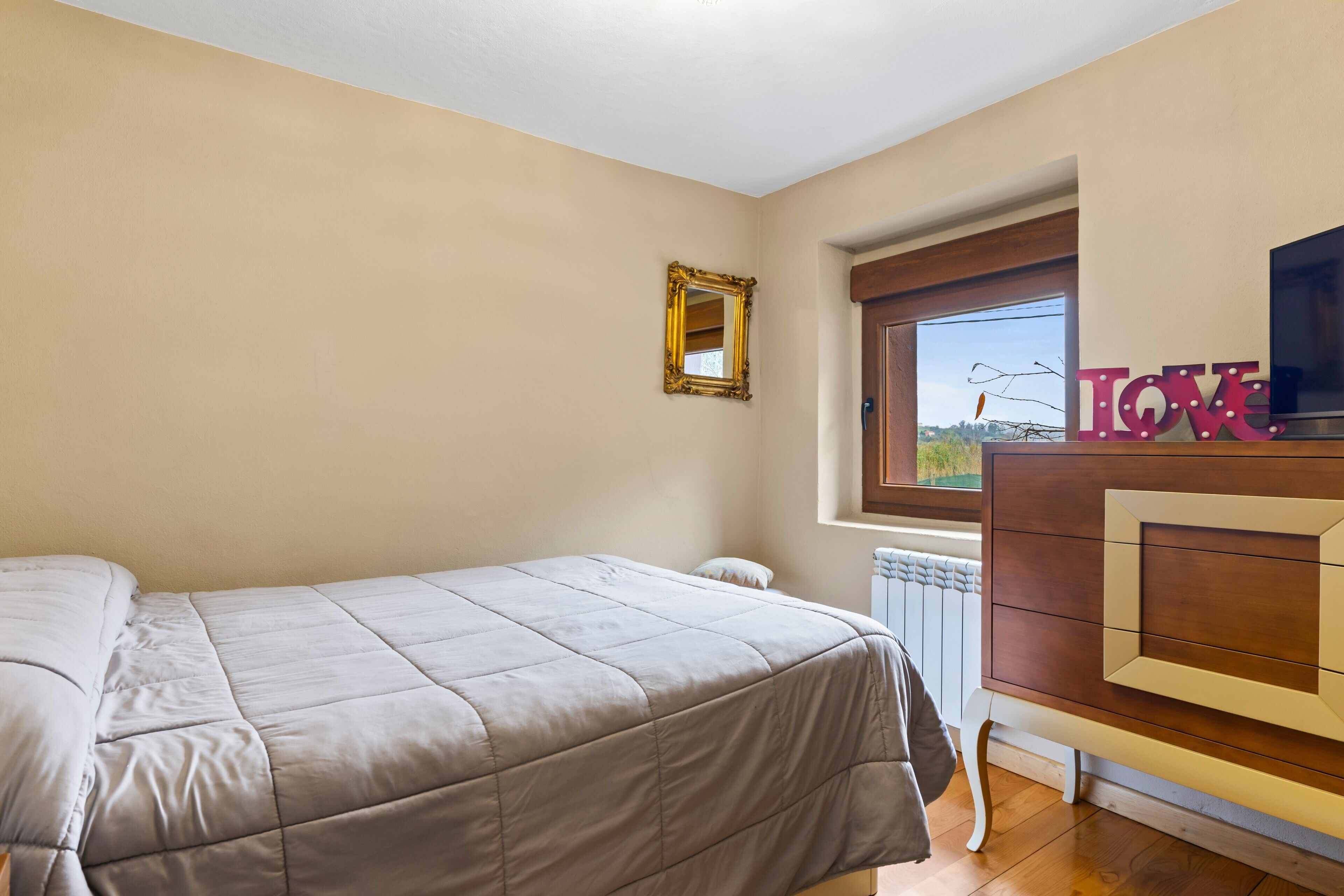 Ein Schlafzimmer mit einem Bett, einem Schminktisch, einem Spiegel und einem Fenster mit Blick.