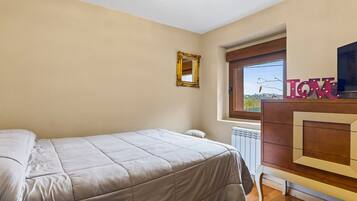 Ein Schlafzimmer mit einem Bett, einem Schminktisch, einem Spiegel und einem Fenster mit Blick.