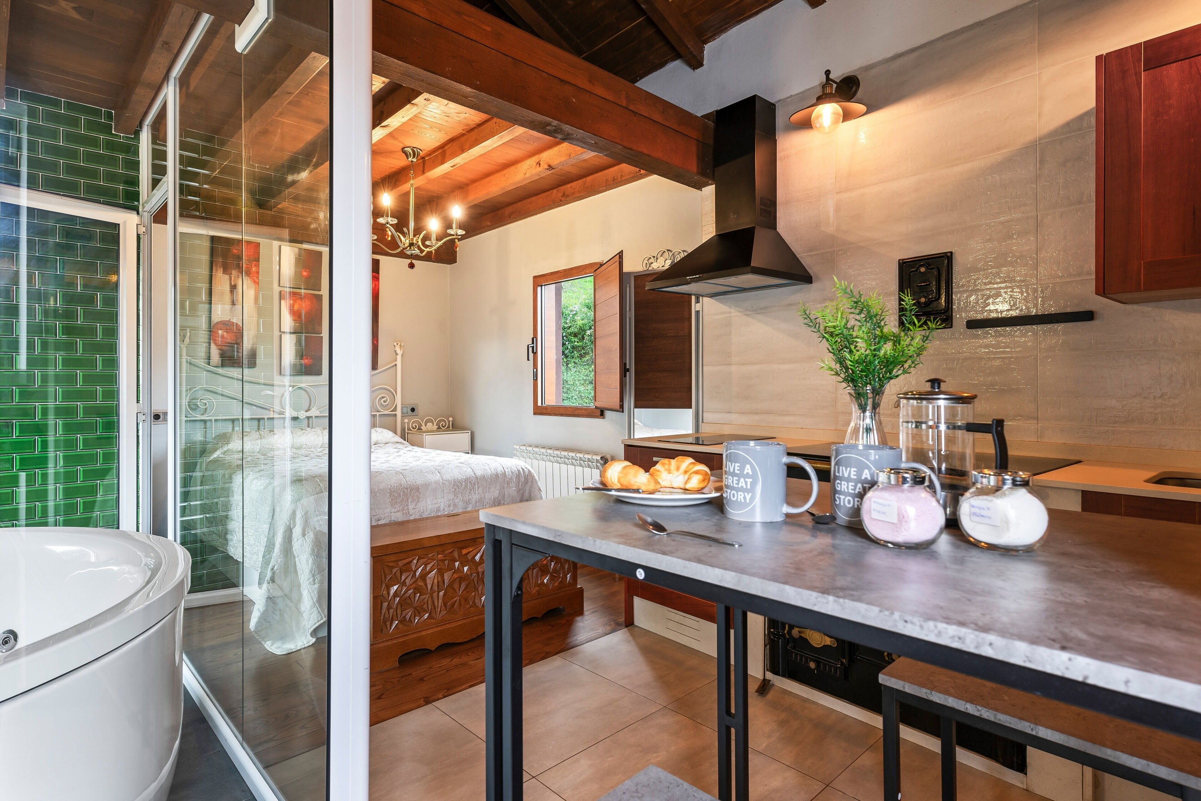 Una cocina moderna con techo de madera, un ventanal de vidrio que da a un dormitorio y un comedor con mesa y sillas.