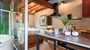 Una cocina moderna con techo de madera, un ventanal de vidrio que da a un dormitorio y un comedor con mesa y sillas.