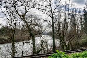 Eine Eisenbahnstrecke mit Bäumen und einem Fluss im Hintergrund.