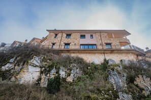 Um edifício com várias andares e varandas, localizado numa encosta rochosa.