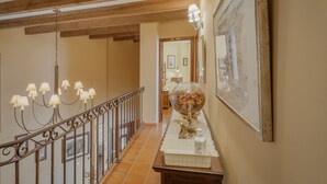 A hallway with a wooden ceiling, a glass vase with flowers, and a framed picture on the wall.