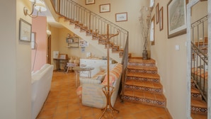 A staircase with ornate railings, a sofa, a small table, and a lamp.