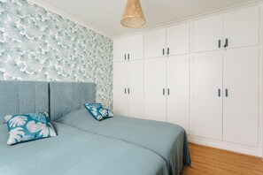 A bedroom with a bed, two pillows, a headboard, a wardrobe, and a hanging light fixture. -  Charming House with Terrace, Parking, and Comfort 10 min from Beach and Harbor (Saint-Trojan-les-Bains)