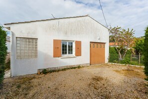 Un petit bâtiment d’un seul étage, à l’extérieur blanc, avec une fenêtre dotée de volets en bois et une porte.