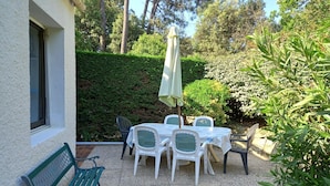 Une terrasse avec une table et des chaises, un banc et un parasol.