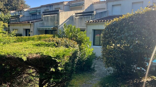 Un quartier résidentiel comprenant plusieurs immeubles, un chemin et une végétation luxuriante.