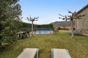 A backyard with a swimming pool, a dining table, chairs, and lounge chairs. - Country House 'Cal Torrentí' with Mountain View, Private Pool and Wi-Fi (Casserres)