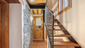 A wooden staircase with a metal railing, a stone wall, and a wooden door leading to another room.