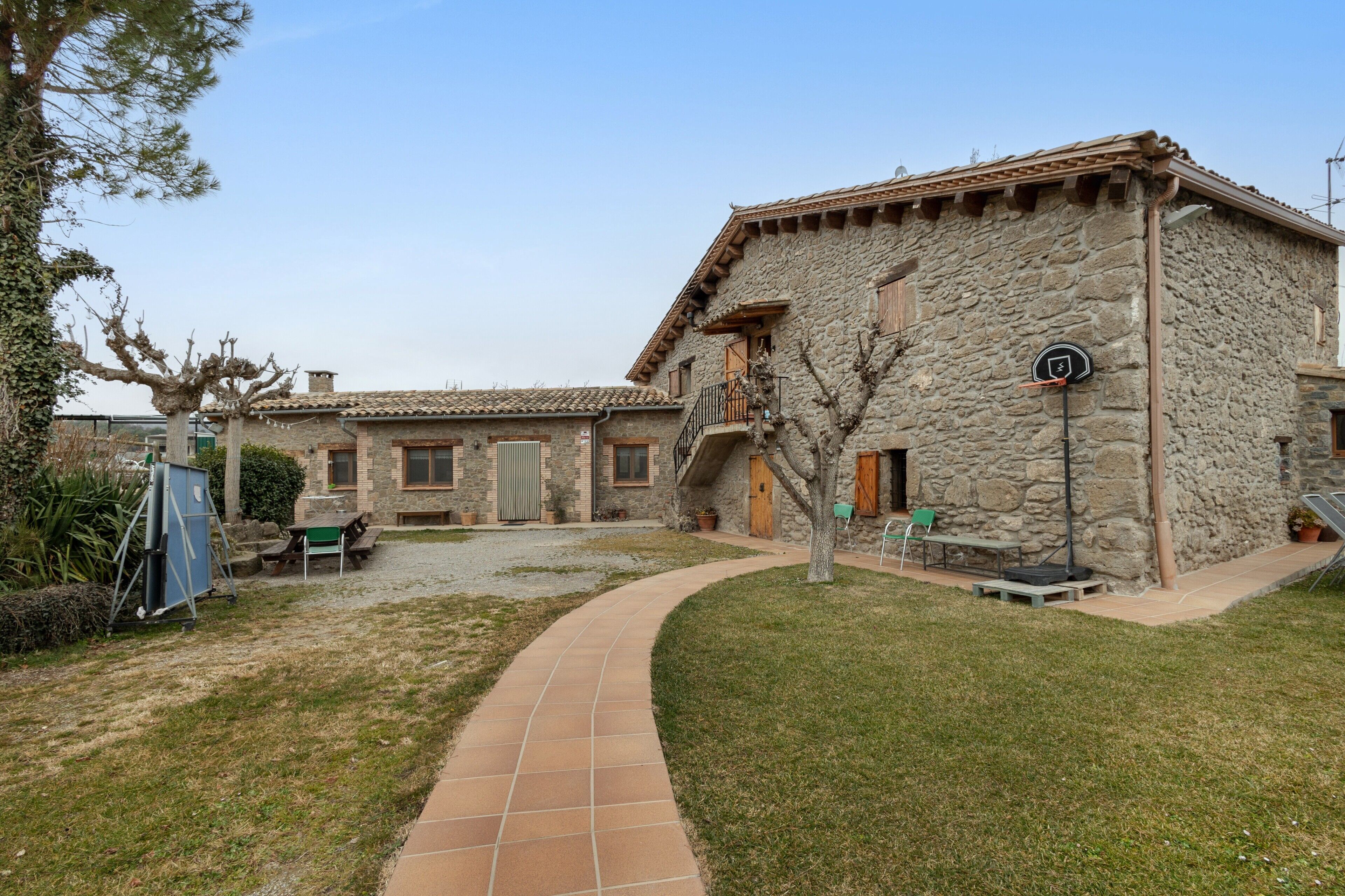 A stone building with a tiled roof, a paved pathway, and outdoor seating.