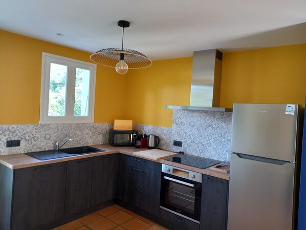 A kitchen with dark cabinets, a microwave, a toaster, and a refrigerator.