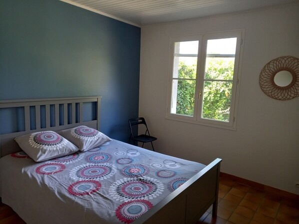 Un dormitorio con cama, ventana y una silla.