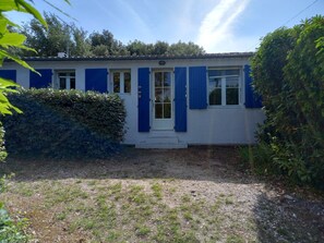 A building with a white exterior and blue shutters, a small front porch, and a well-maintained garden.