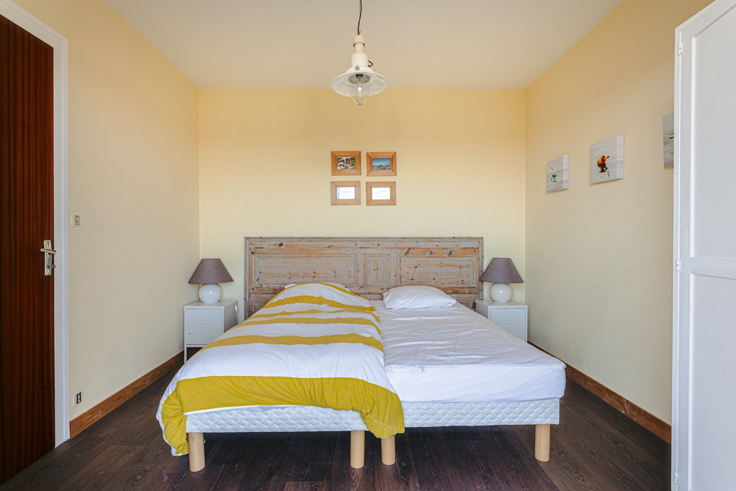 A double bed with a wooden headboard, two bedside tables with lamps, and a ceiling light fixture.