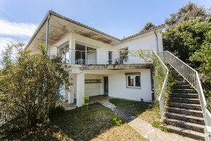 Une maison à deux étages avec un balcon, un escalier et un jardin.
