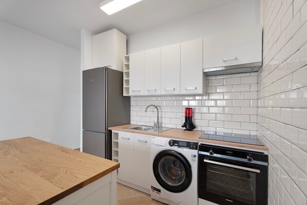 A compact kitchen with a washing machine, oven, and a sink.