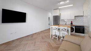 A modern kitchen with white cabinets, a built-in oven, and a washing machine.