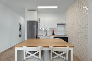 Una cucina moderna con mobili bianchi, un tavolo di legno e due sedie bianche.