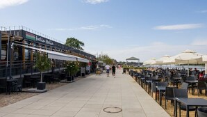An outdoor dining area with tables and chairs, a storefront named 'bella Italia', and a covered seating area with umbrellas. - Powiśle 2-Bedroom Apartment (Warszawa)