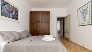 A bedroom with a bed, a wardrobe, and a door leading to another room. - Powiśle 2-Bedroom Apartment (Warszawa)