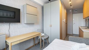 A modern hotel room with a wooden desk, a white bed, and a wardrobe. - Reymonta 24 Studio with FREE PARKING (Katowice)