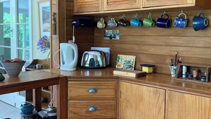 A wooden kitchen with cabinets, a countertop, and various kitchen appliances. - Light-Filled Hira Home (Hira)