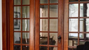 Una puerta de madera con paneles de vidrio, un comedor con mesa y sillas, y un sofá azul en primer plano.